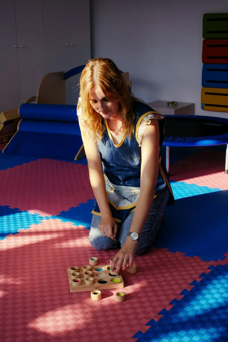 An adult arranging wooden learning materials for a teaching activity.