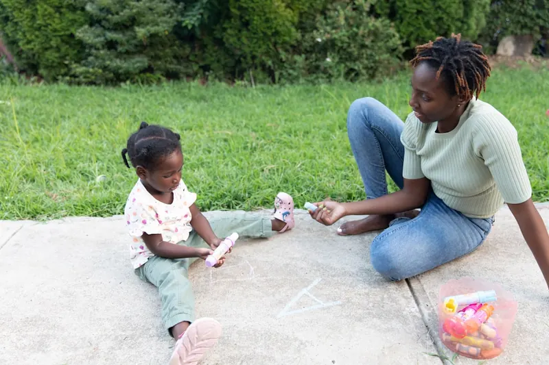 A parent and child engaged warmly in an activity together outdoors.