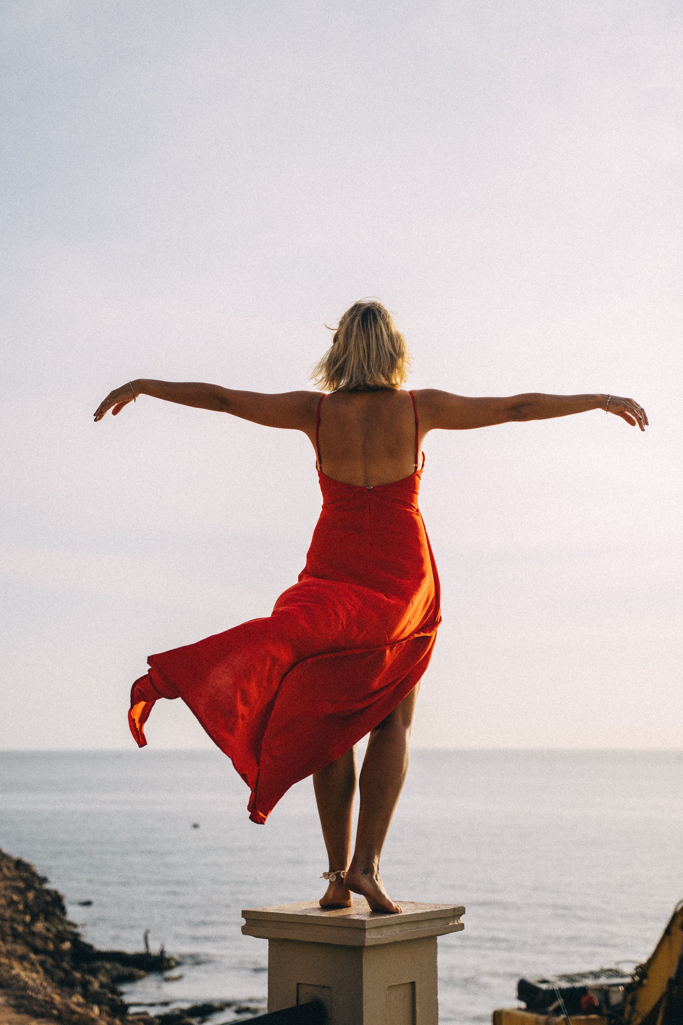 woman in red dress facing the sea