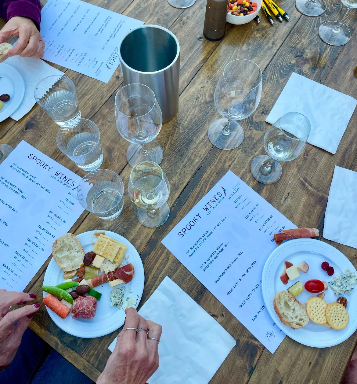 An overhead photo of a table with wine glasses on it and food alongside our spooky flight menus. This is an wine educational event hosted on The Starlight Patio for our members.