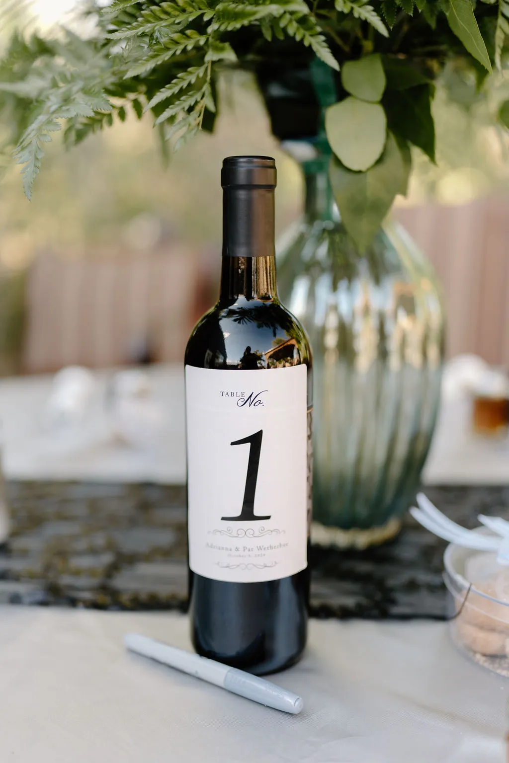 A wine bottle table number with greenery on a wedding reception table at The Betsy