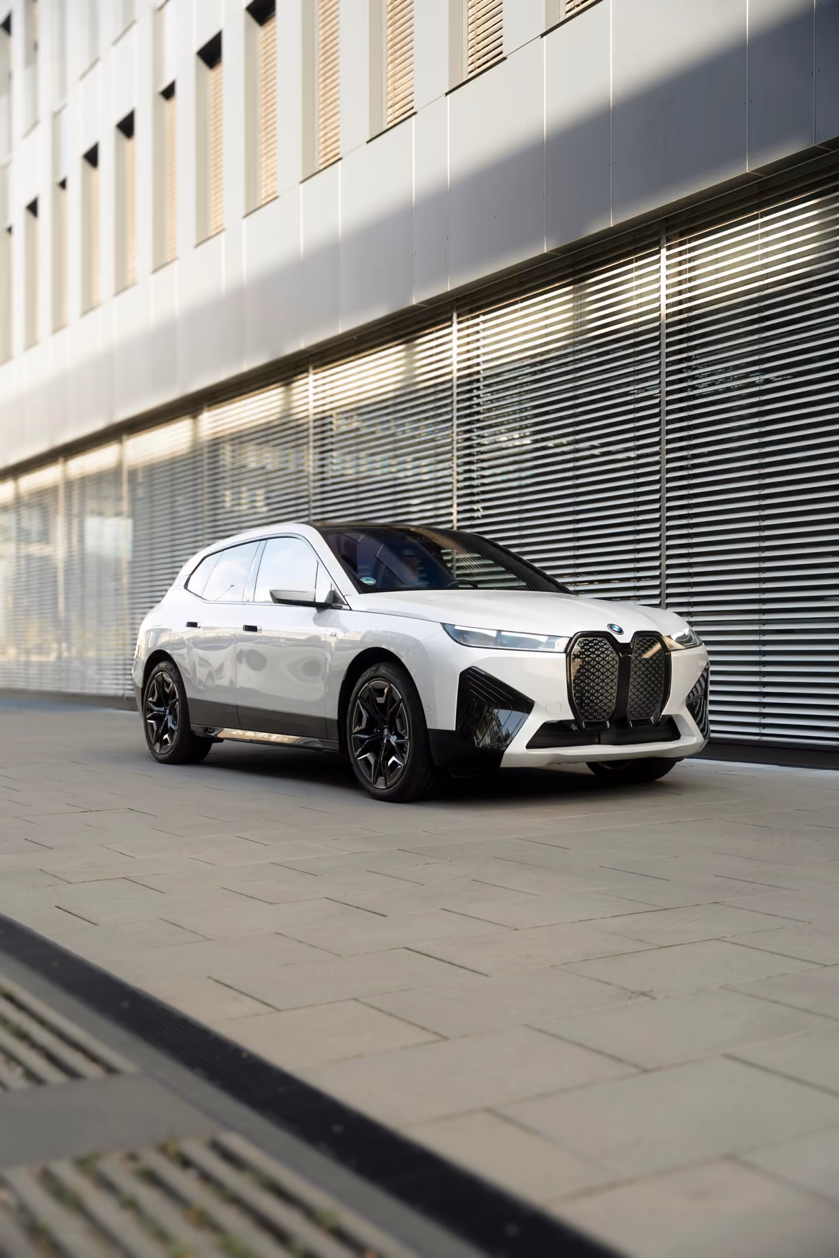 Weißer BMW iX vor einem modernen Bürogebäude