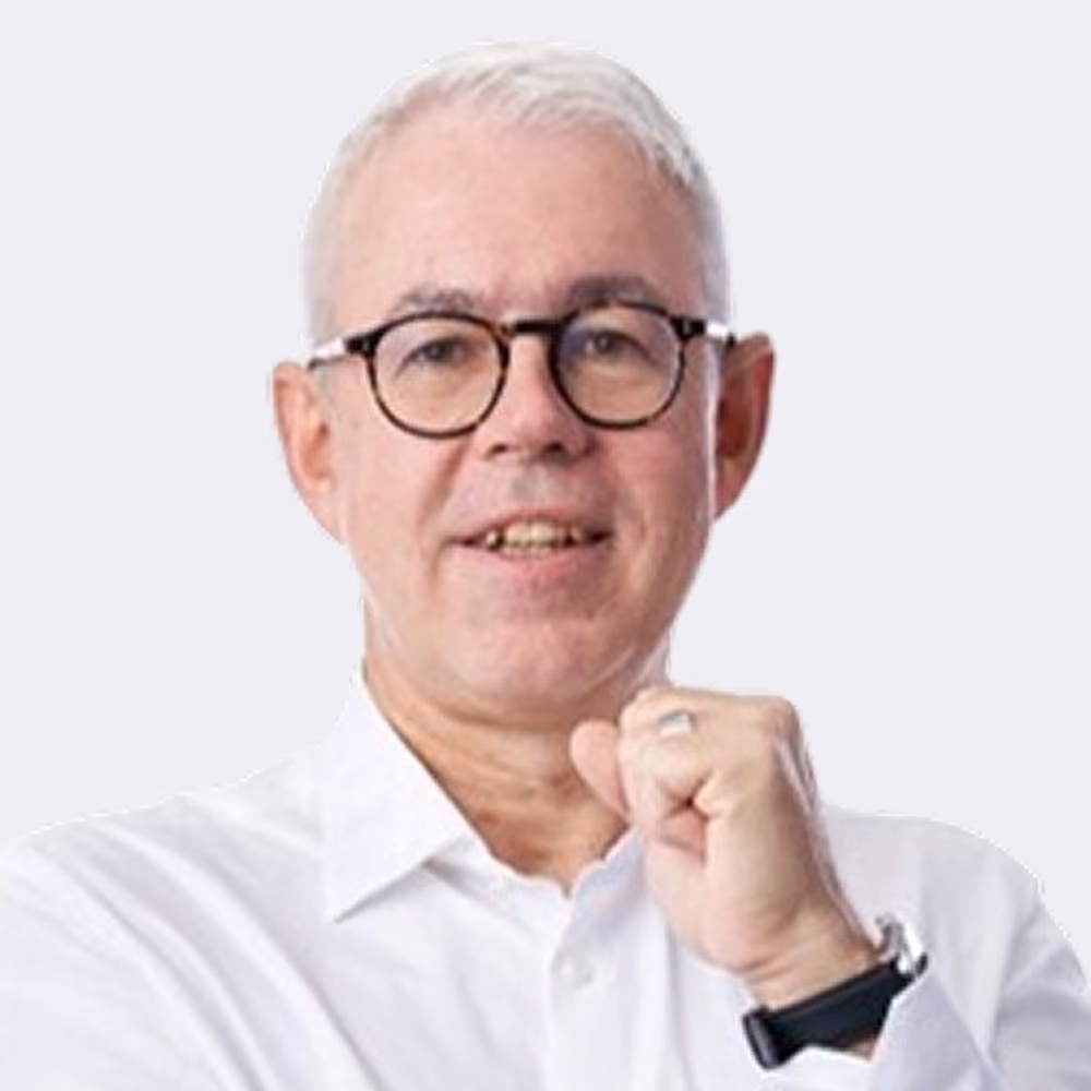 Älterer Mann mit weißem Hemd und Brille, hebt leicht die Faust vor sich.