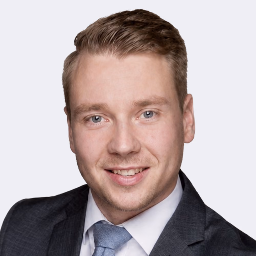 Älterer Mann mit weißem Hemd und Brille, hebt leicht die Faust vor sich.