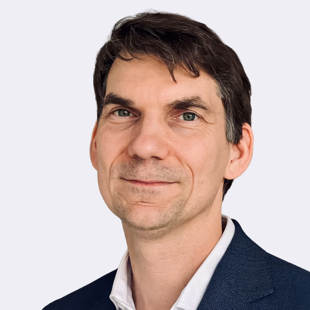 Älterer Mann mit weißem Hemd und Brille, hebt leicht die Faust vor sich.