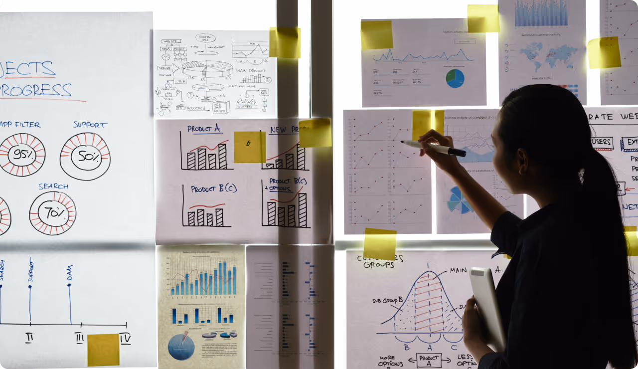 Femme analysant des graphiques de performance collés sur une vitre, gestion de projet en entreprise, analyse de données