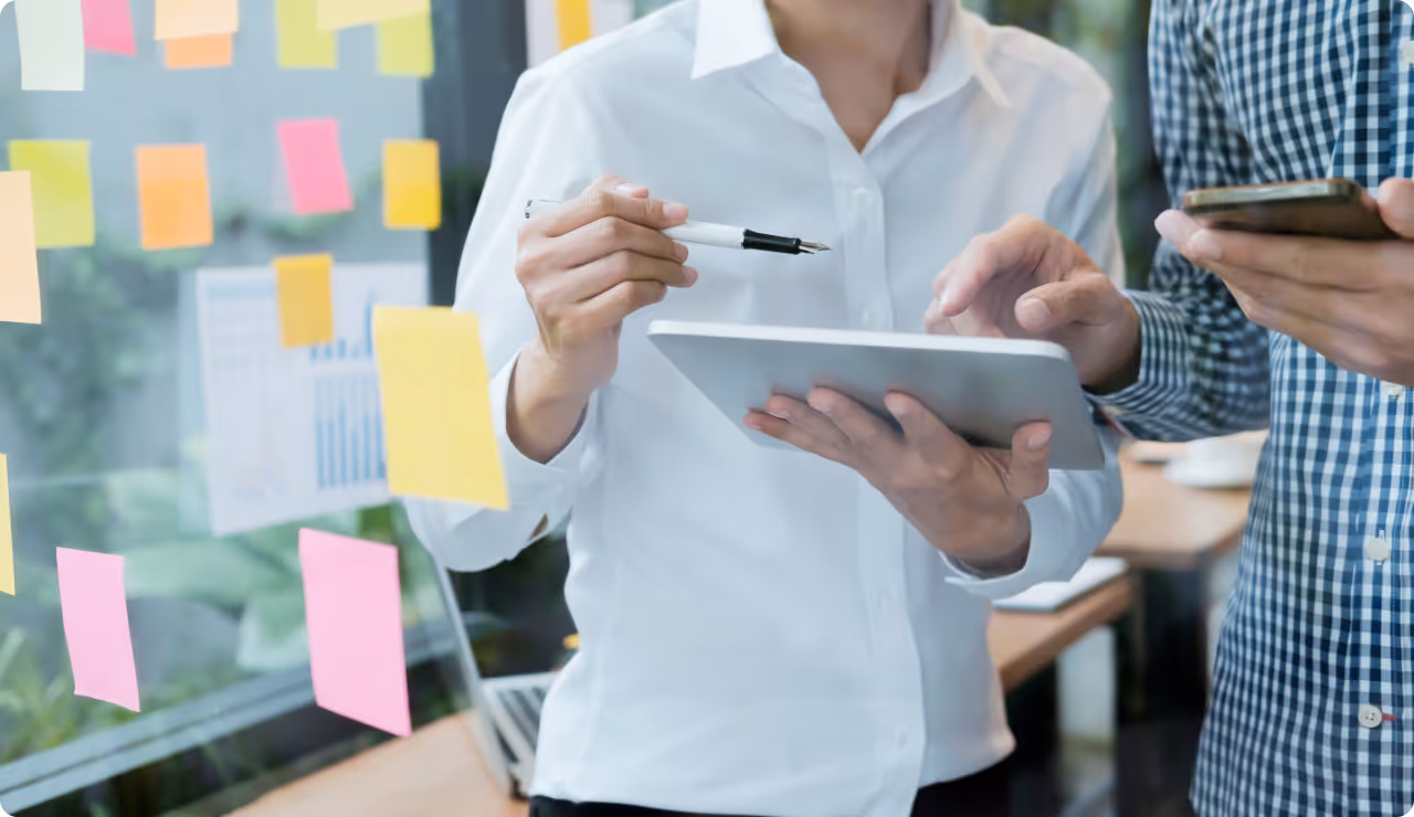 Deux collègues collaborant sur des post-it colorés, séance de brainstorming et gestion de projet efficace