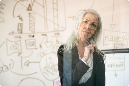 Manager en réflexion stratégique devant un tableau de planification d’équipe.