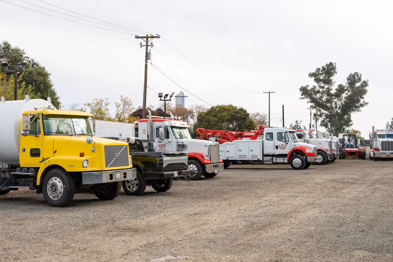 Fleet maintenance service with line of work trucks and utility vehicles parked in yard for heavy-duty repair and service.
