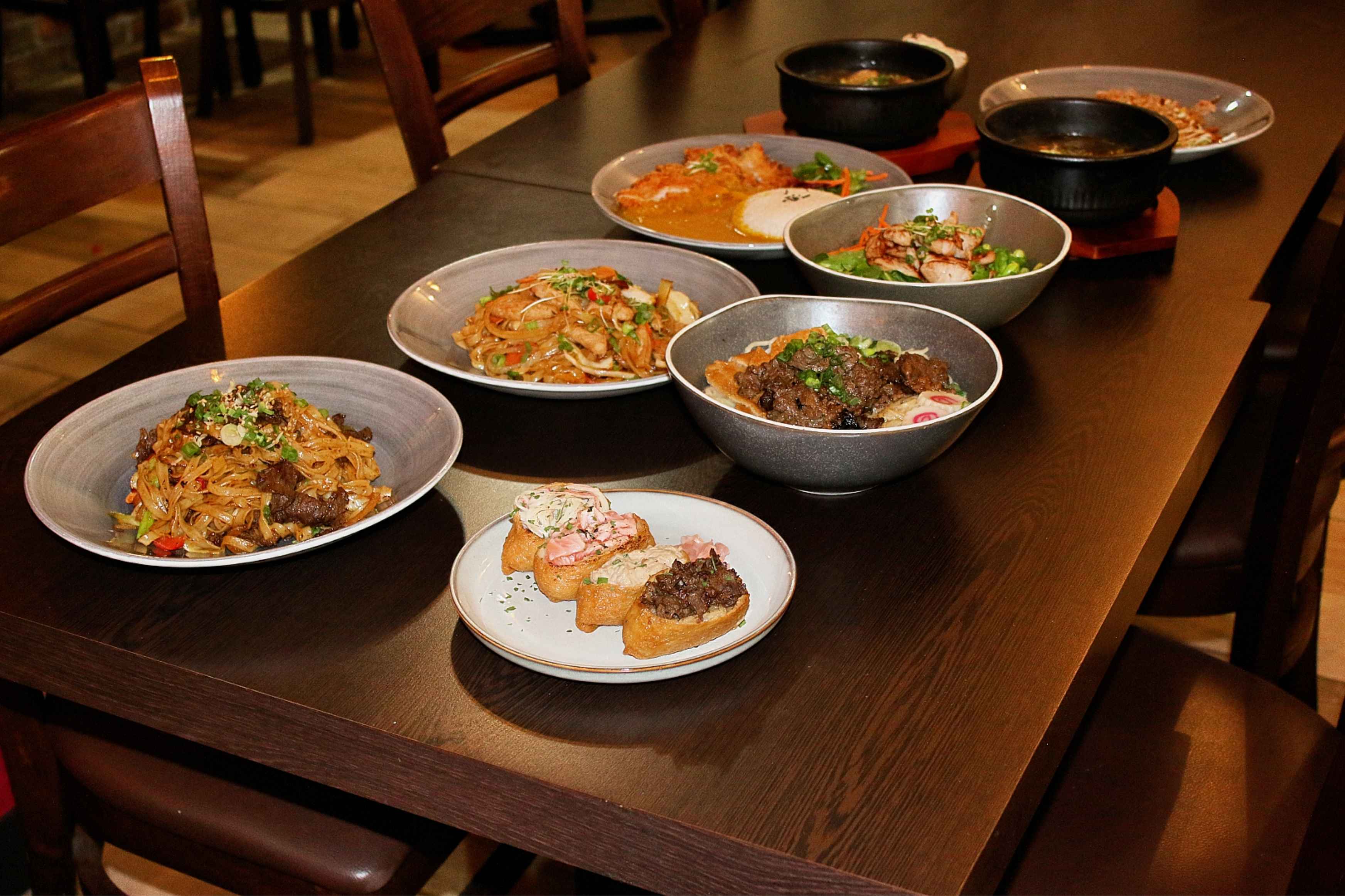 Korean dishes, including rice bowls, noodles, soups, and shared plates, ready for group dining.