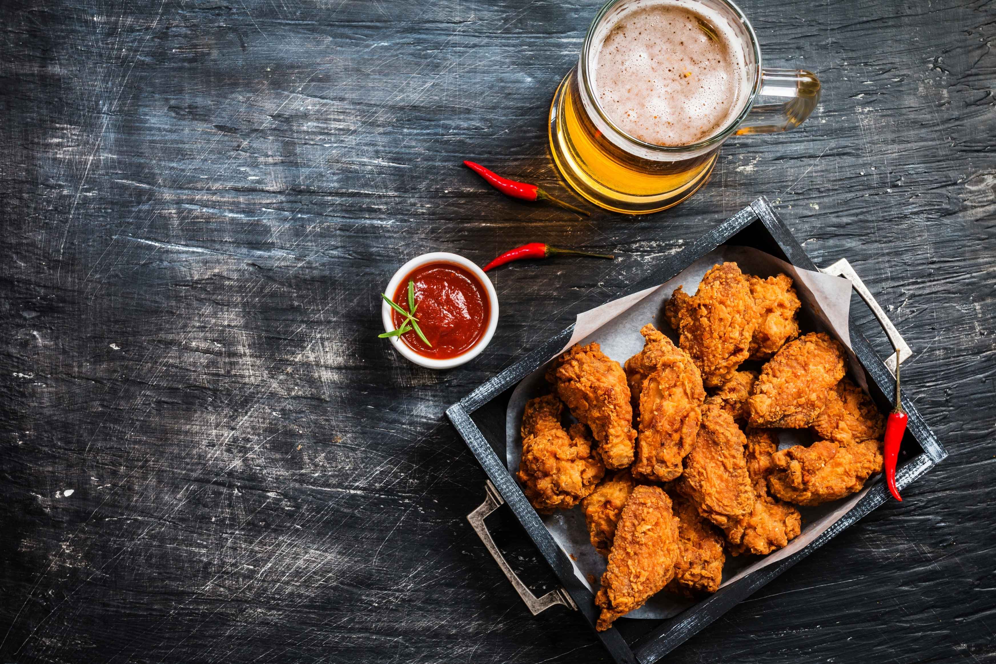 Crispy Korean fried chicken with spicy sauce, red chillies and a cold glass of beer.