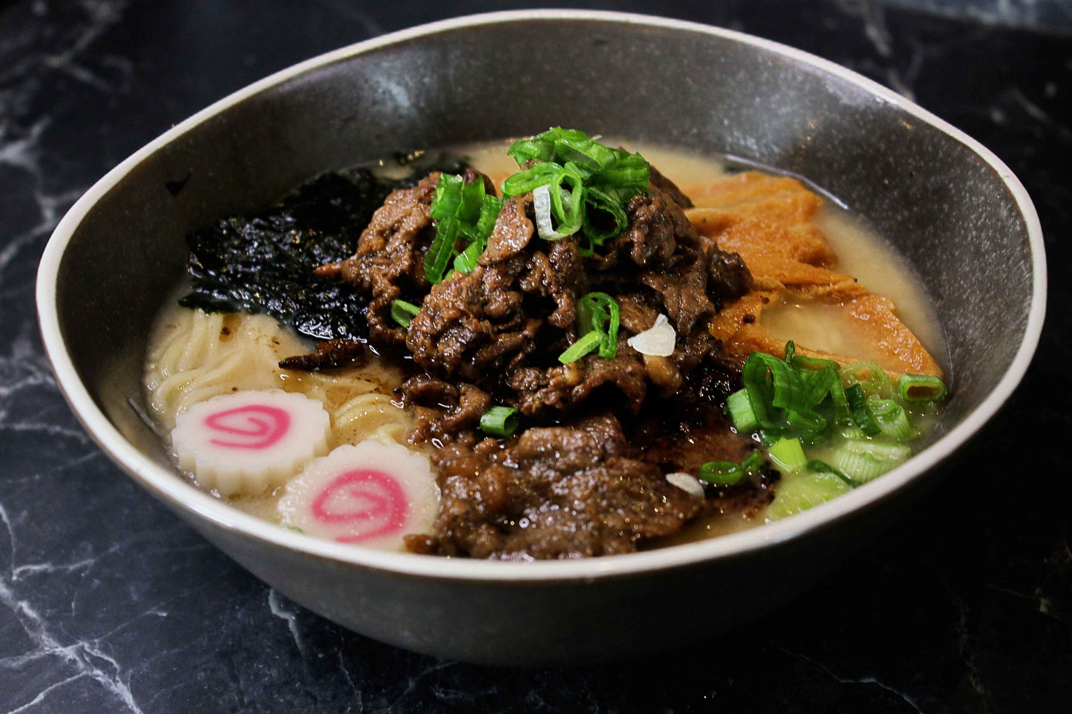 Hot Korean ramen bowl topped with savoury beef, greens and traditional garnishes.