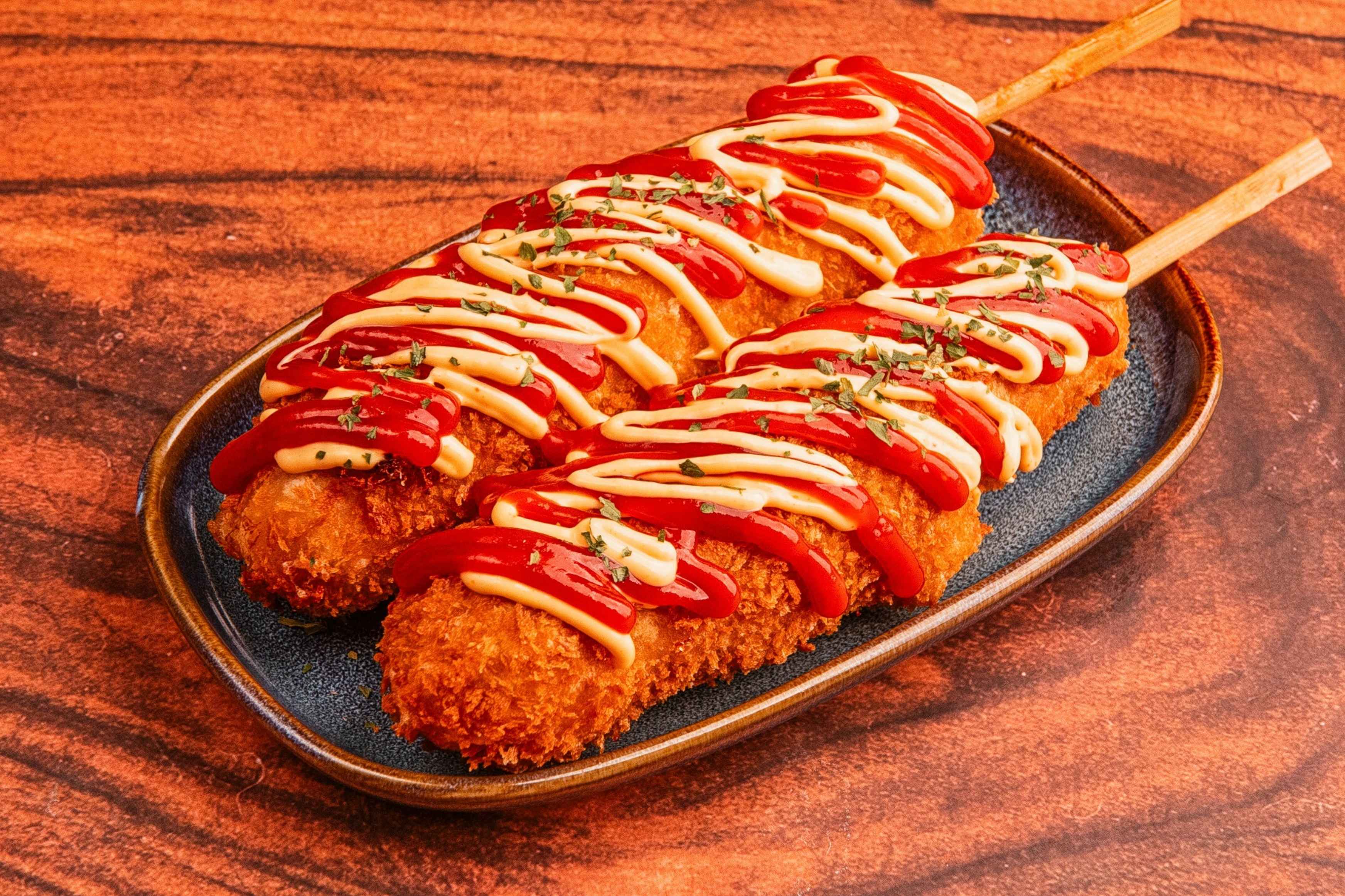 Crispy Korean street food corn dogs drizzled with ketchup and mayonnaise.