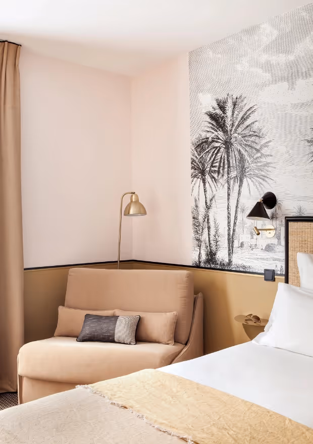 Chambre confortable avec fauteuil près du lit chez Orso Hotels Paris, ambiance chaleureuse et luxe discret.