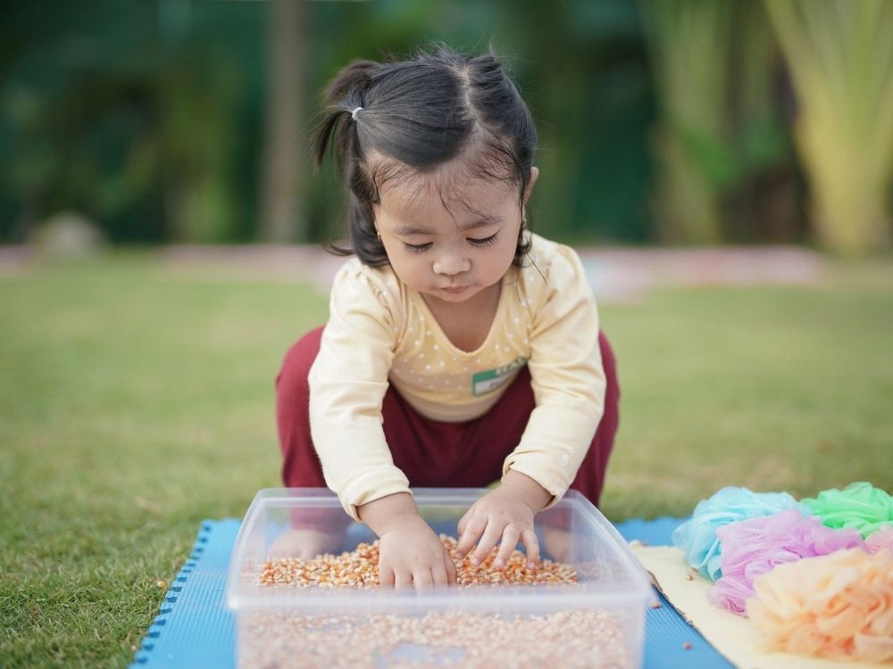 A toddler playing during daycare in a sandbox.
