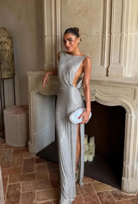 Model in a silver crystal-embellished Retrof&ecirc;te gown with a high slit, holding a beaded clutch