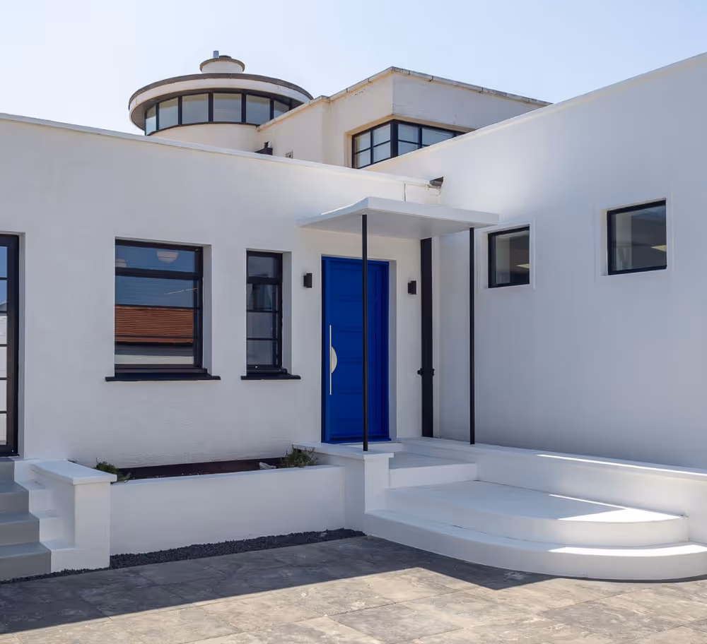 A white house with a blue door and steps.