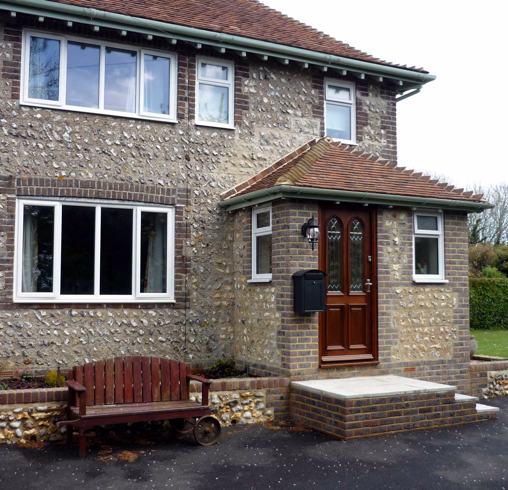 A brick house with a wooden bench in front of it.