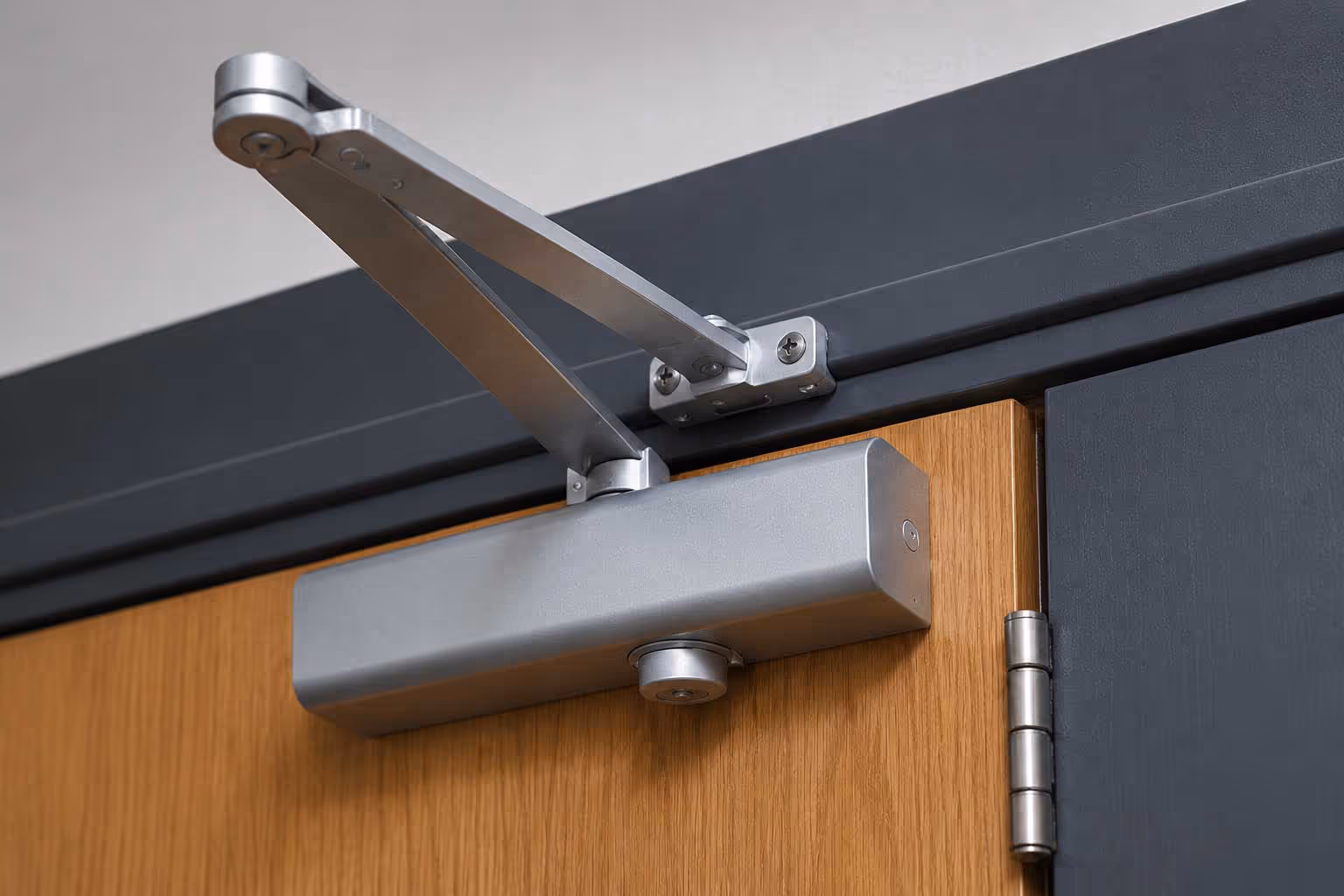 Metal door closer installed on a wooden door to ensure automatic closing.