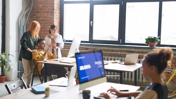 An office with people gathered around a computer screen.