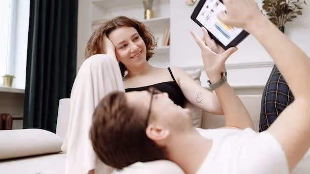 Smiling couple relaxing at home while looking at a tablet together.