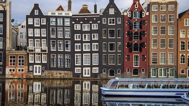 A picture of houses and a canal boat in Amsterdam.
