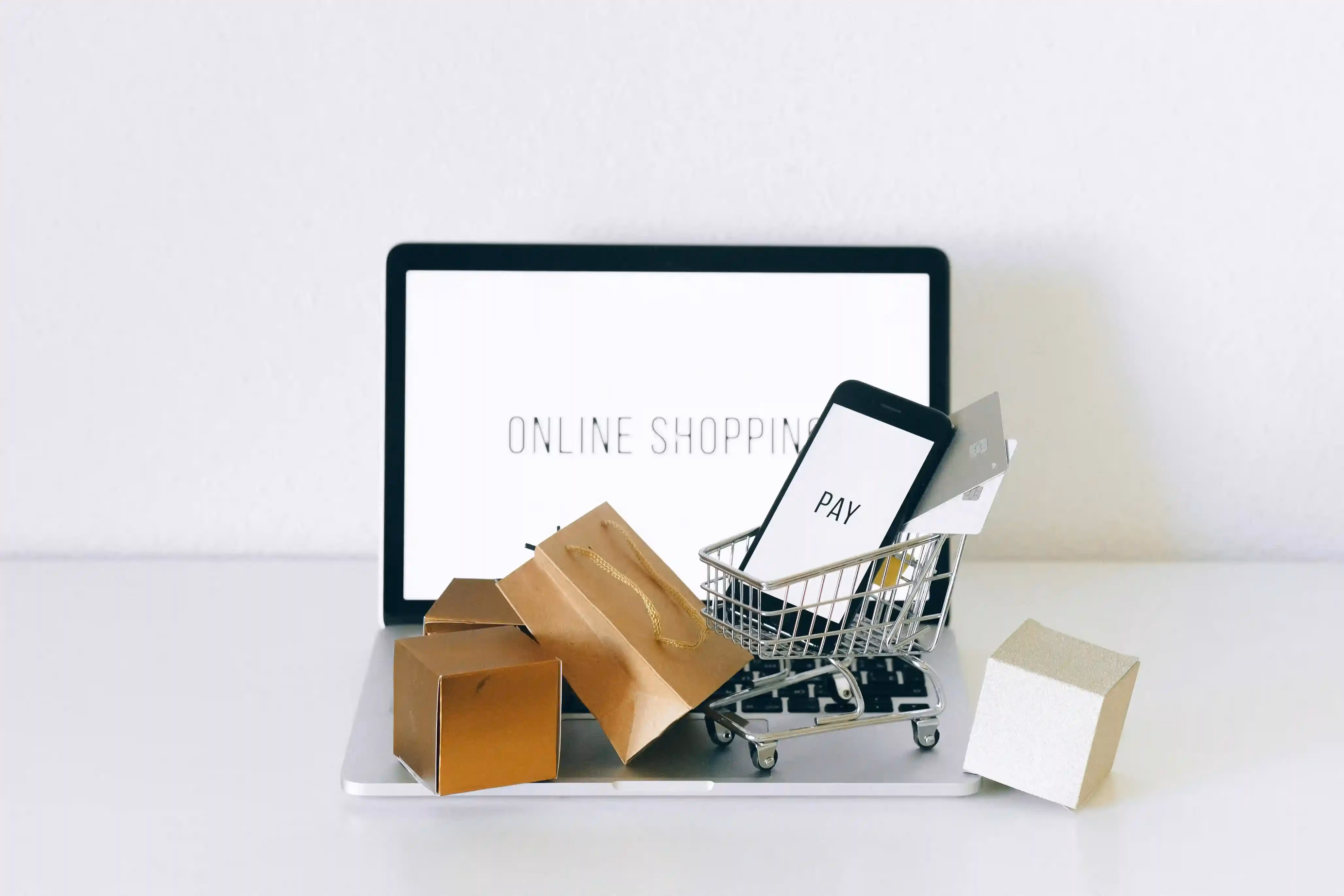 Online shopping concept with laptop, shopping cart, phone, credit card, and packages.