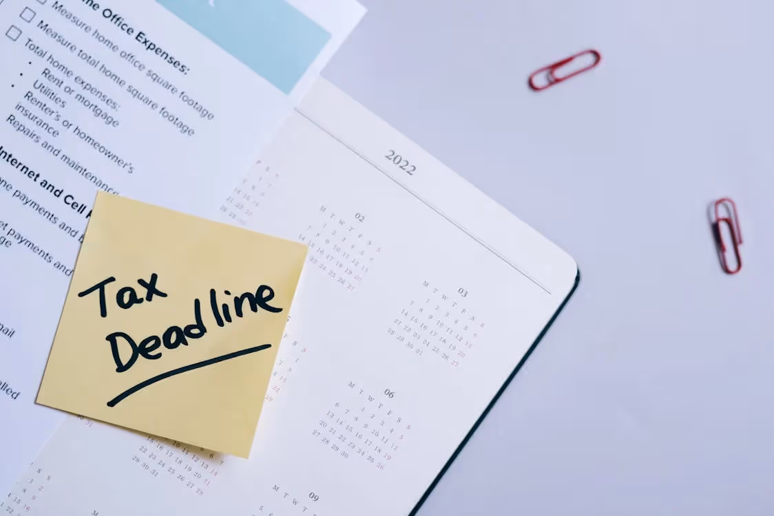 Sticky note reading "Tax Deadline" on a 2022 calendar and tax documents.