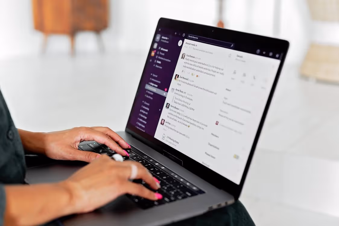 Person using a laptop with the Slack messaging app open on the screen.