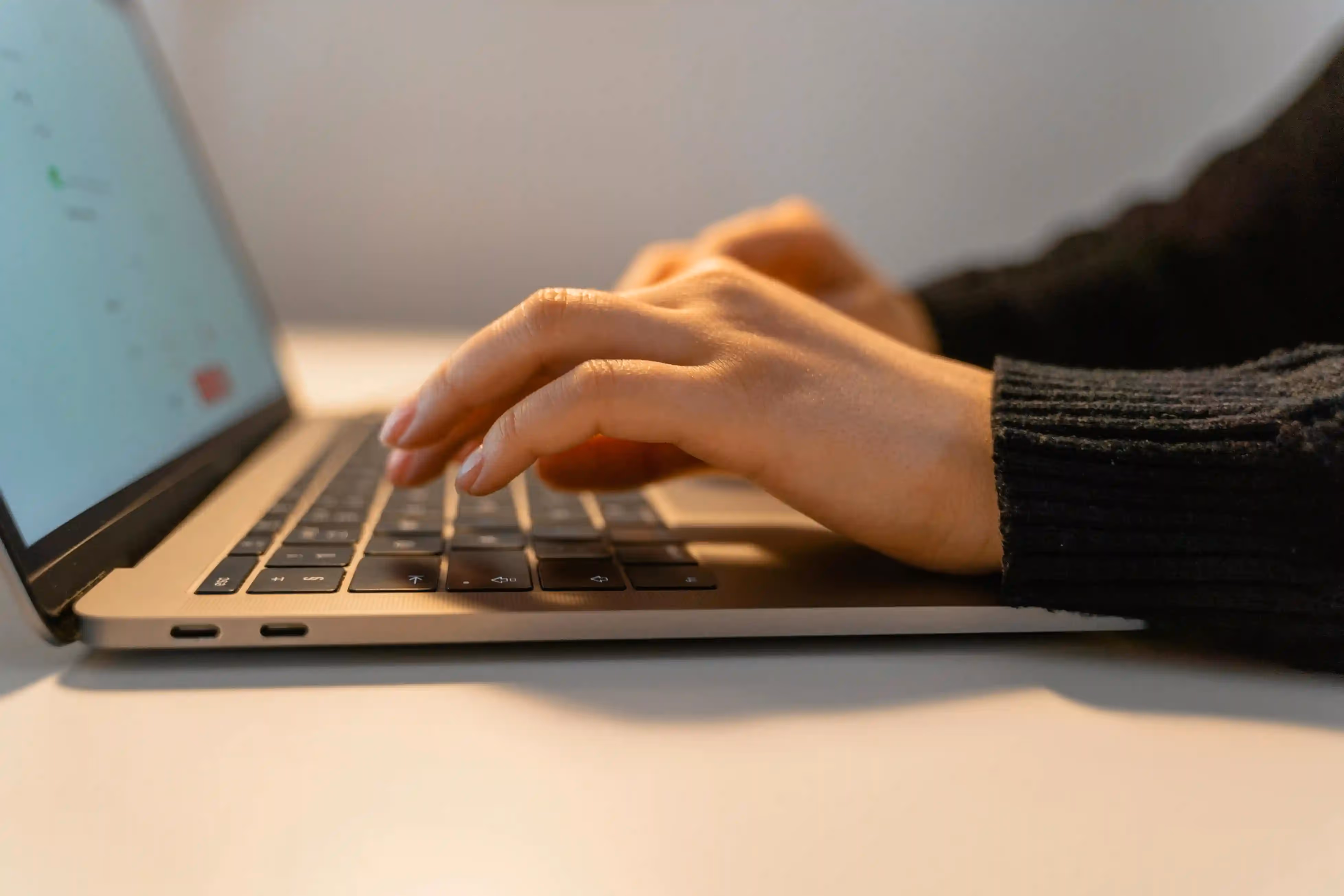 Close-up of hands typing on a laptop keyboard.