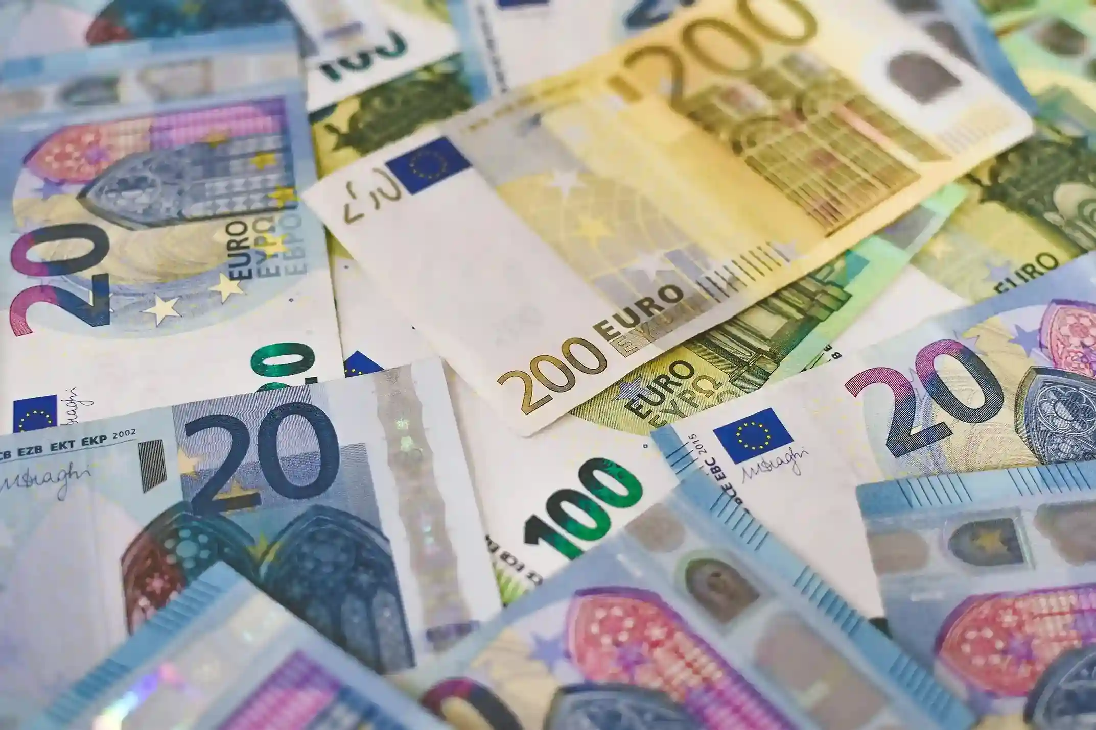 Euro banknotes in €20, €100, and €200 denominations scattered.
