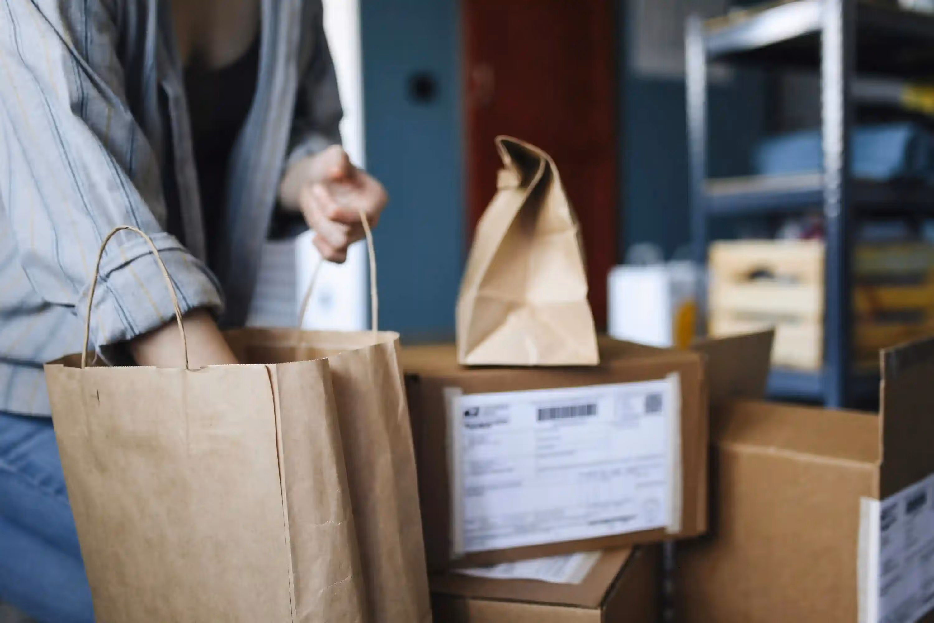 Person packing paper bags and boxes for shipping.
