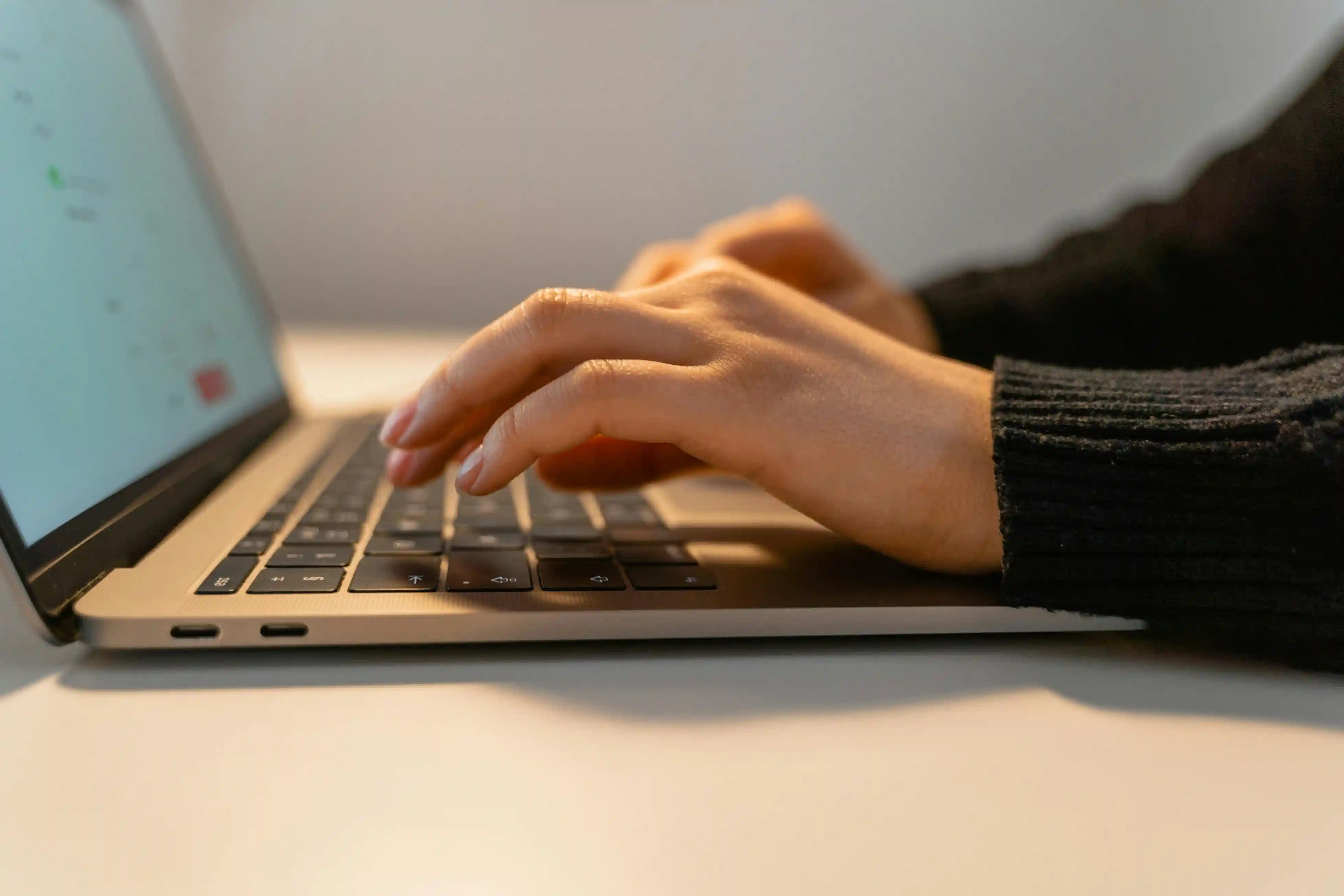 Hands typing on a laptop keyboard at a desk.