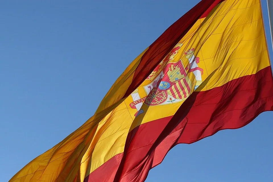 Spanish flag waving in the wind against a clear blue sky.