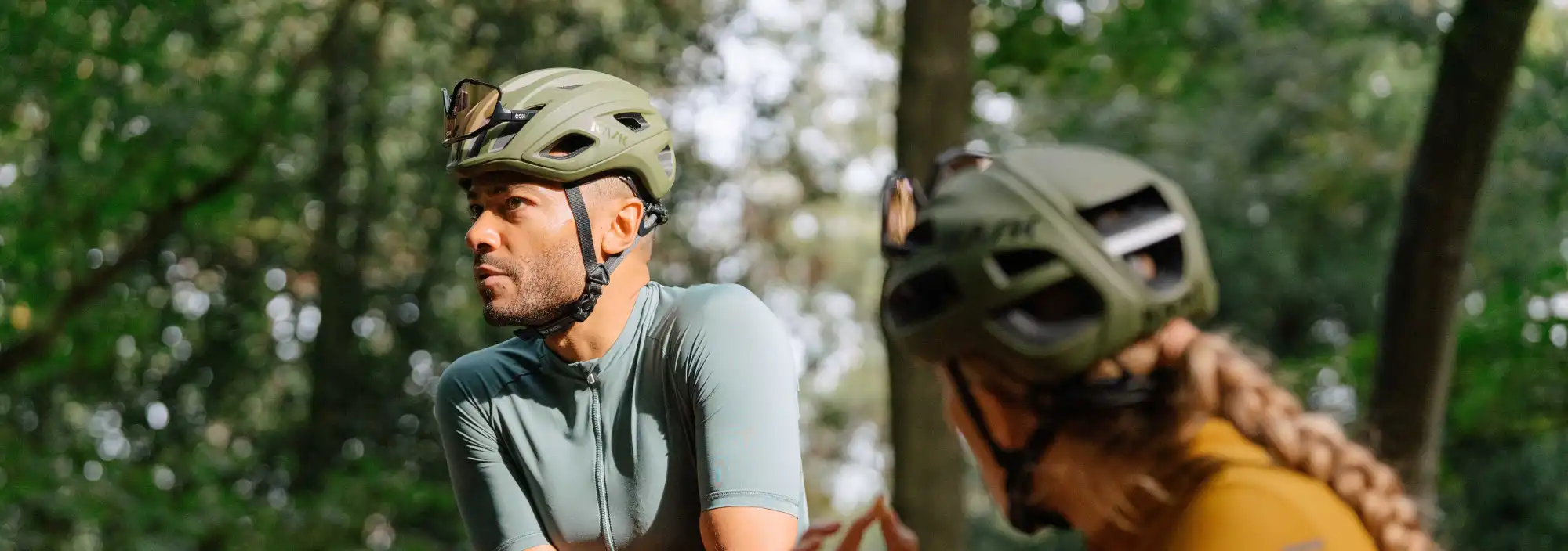 A man and a woman wearing helmets in the woods