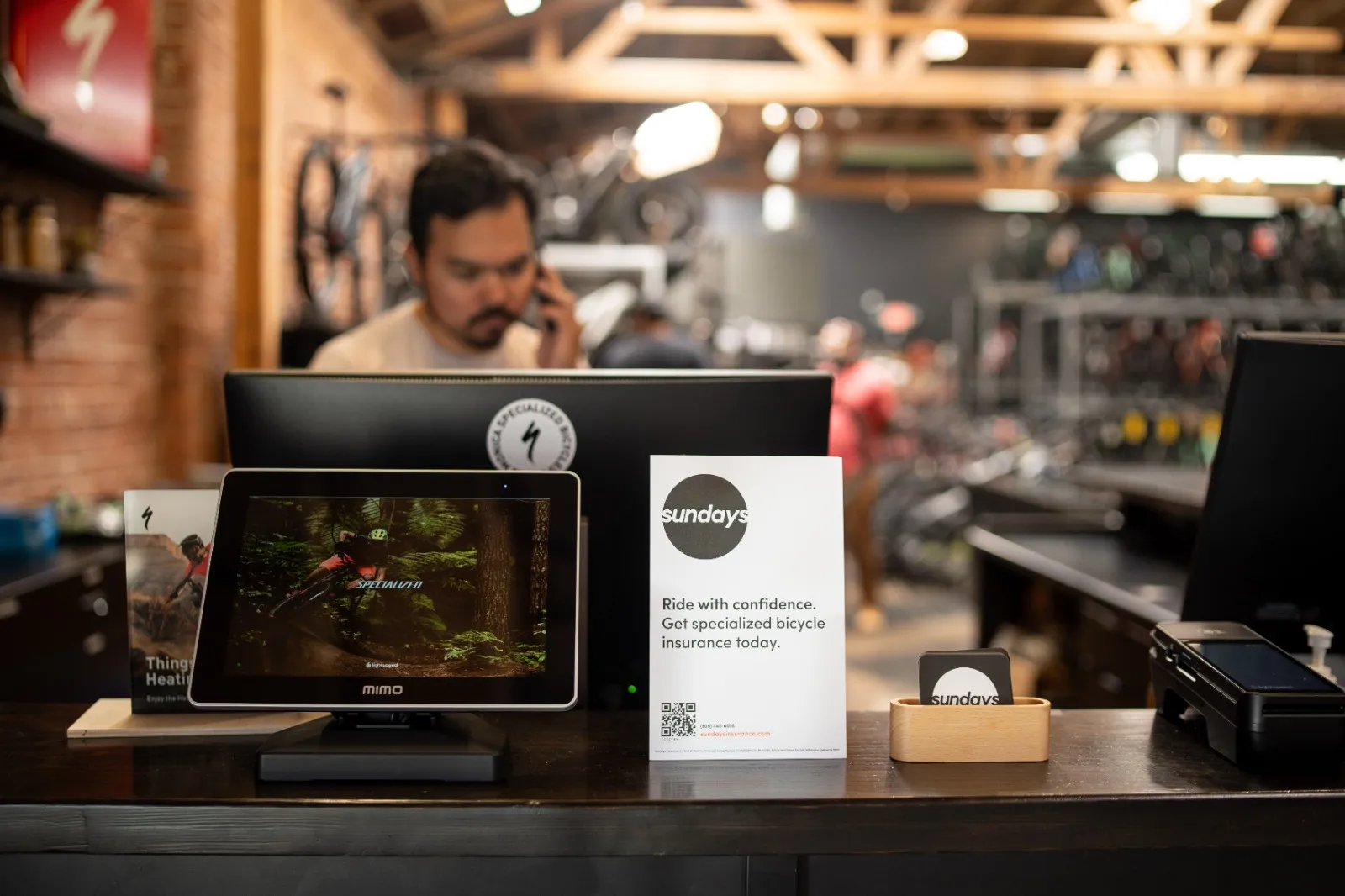 A man sitting in front of a laptop computer in bicycle shop