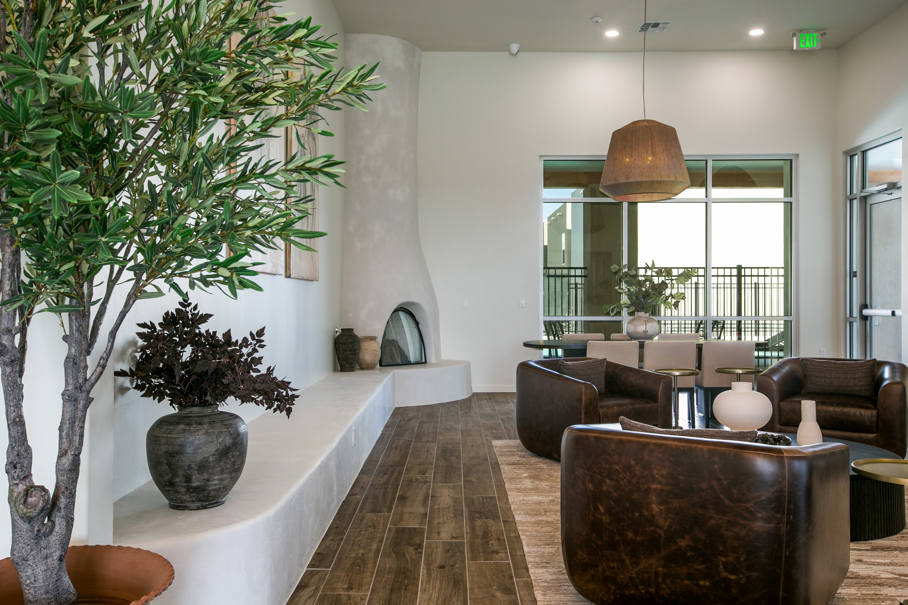 Modern clubhouse lounge with a fireplace, bar seating, and a large window overlooking an outdoor space, at The Eleanor at Rio Rancho in Rio Rancho, NM.