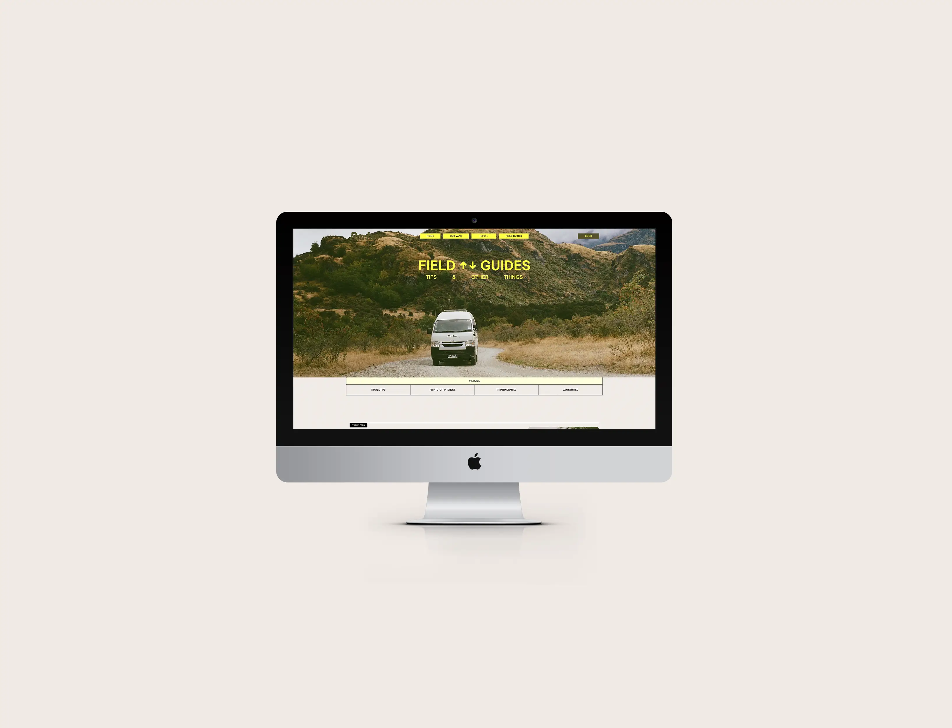 iMac screen displaying a camper van on a rural road with website header reading FIELD GUIDES.
