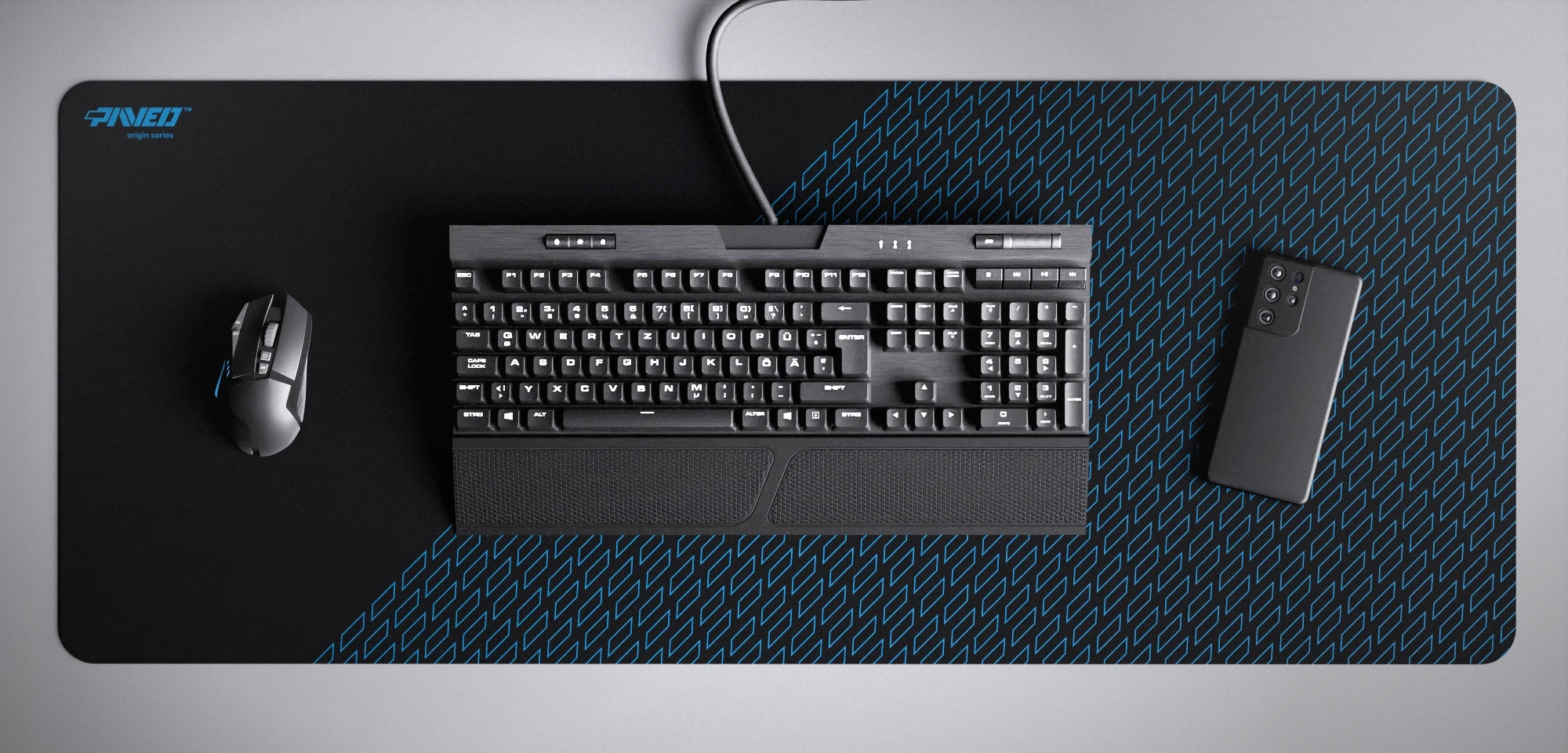 Top view of Night Sky Pathfinder XXL deskmat 1000mm x 400mm left-handed variant featuring geometric tiled pattern in blue and black, water-resistant antimicrobial polyester surface, shown with full-size mechanical keyboard, gaming mouse, and smartphone for scale, ultra-lightweight odour-free AreoFlex microruber base, stitch-free professional finish.