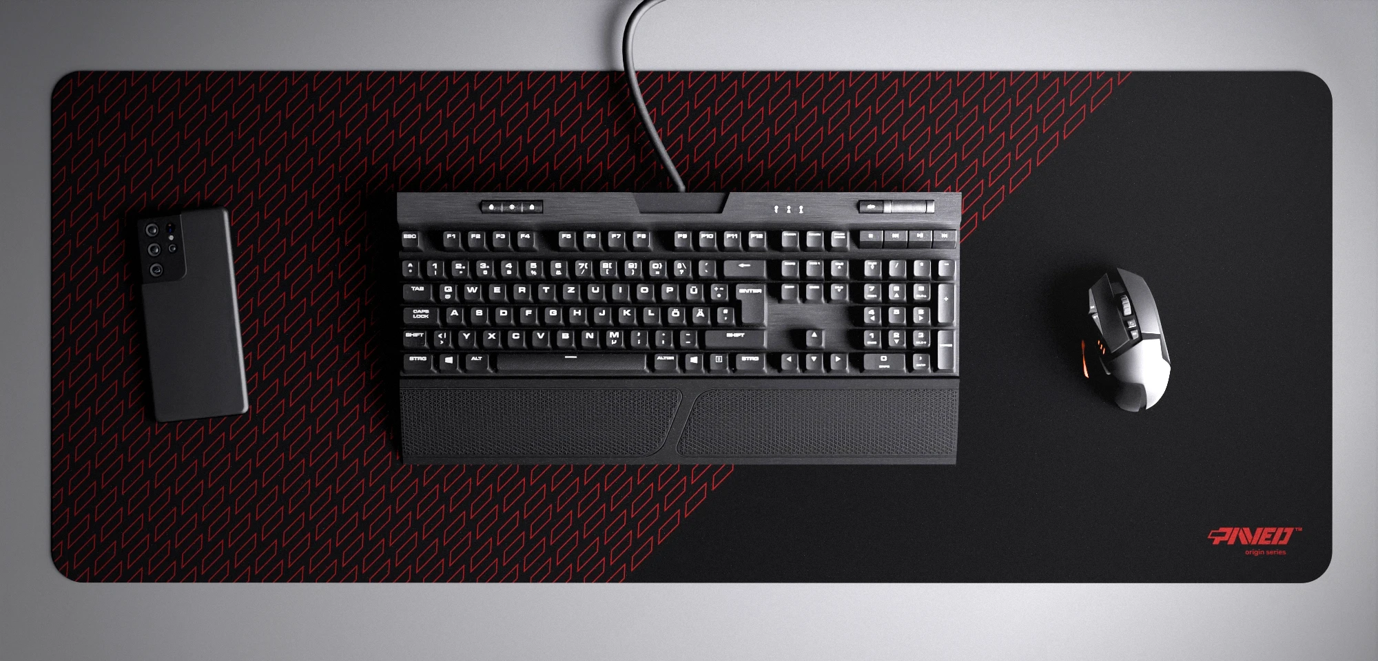 Top view of Night Imperial Pathfinder XXL deskmat 1000mm x 400mm right-handed variant with minimalistic geometric tiled pattern in red and black, hydrophobic easy-to-clean antimicrobial surface, shown with full-size mechanical keyboard, gaming mouse, and smartphone for scale, 600% lighter non-slip base with no rubbery smell, durable stitch-free edges.