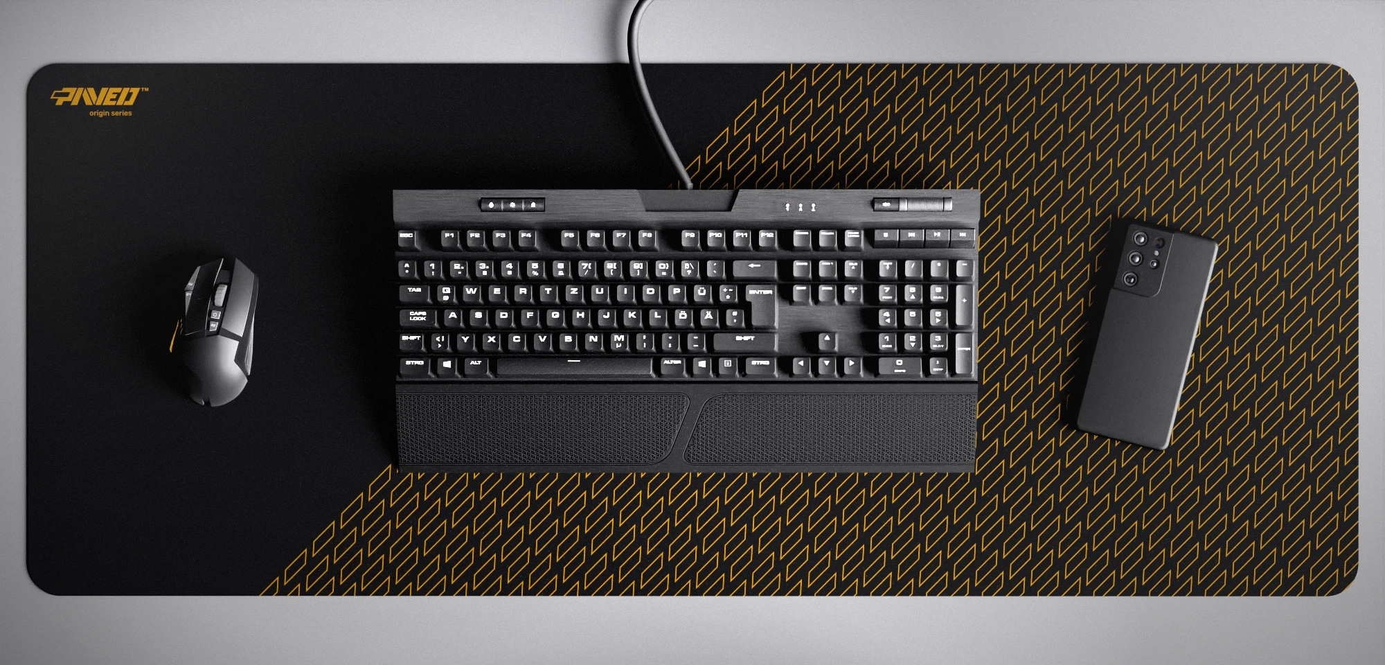 Top view of Night Desert Pathfinder XXL deskmat 1000mm x 400mm left-handed variant featuring geometric tiled pattern in deep yellow and black, water-resistant antimicrobial polyester surface, shown with full-size mechanical keyboard, gaming mouse, and smartphone for scale, ultra-lightweight odour-free AreoFlex microruber base, stitch-free professional finish.