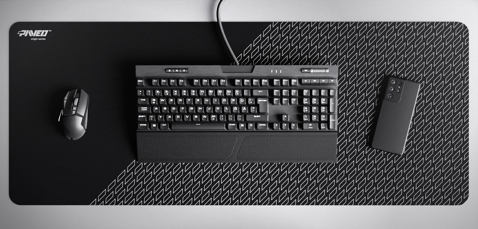 Top view of Night Pathfinder XXL deskmat 1000mm x 400mm left-handed variant featuring geometric tiled pattern in white and black, water-resistant antimicrobial polyester surface, shown with full-size mechanical keyboard, gaming mouse, and smartphone for scale, ultra-lightweight odour-free AreoFlex microruber base, stitch-free professional finish.