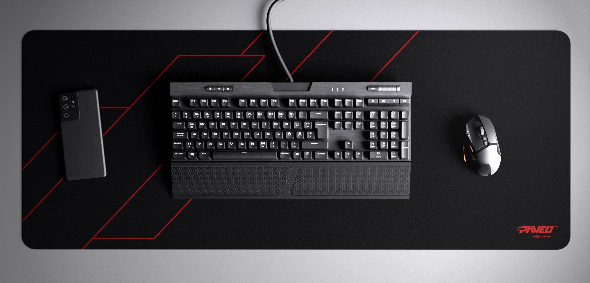 Top view of Night Imperial Formula XXL deskmat 1000mm x 400mm right-handed variant with minimalistic geometric angular line pattern in red and black, hydrophobic easy-to-clean antimicrobial surface, shown with full-size mechanical keyboard, gaming mouse, and smartphone for scale, 600% lighter non-slip base with no rubbery smell, durable stitch-free edges.