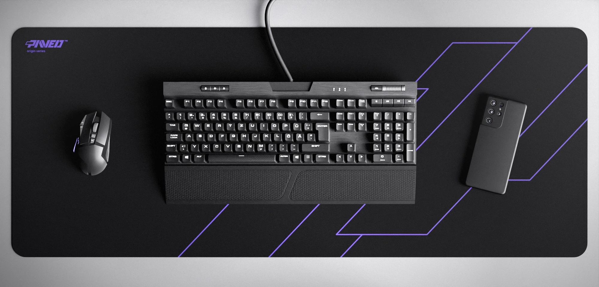 Top view of Night Amethyst Formula XXL deskmat 1000mm x 400mm left-handed variant featuring geometric angular line pattern in purple and black, water-resistant antimicrobial polyester surface, shown with full-size mechanical keyboard, gaming mouse, and smartphone for scale, ultra-lightweight odour-free AreoFlex microruber base, stitch-free professional finish.