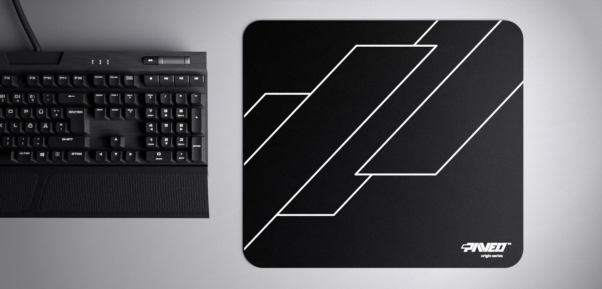 Top view of Night Formula M size mousepad 360mm x 320mm right-handed variant with geometric angular line pattern in white and black, hydrophobic easy-to-clean surface with antimicrobial properties, shown with full-size mechanical keyboard for scale, 600% lighter with no rubbery odour base, durable stitch-free finish.