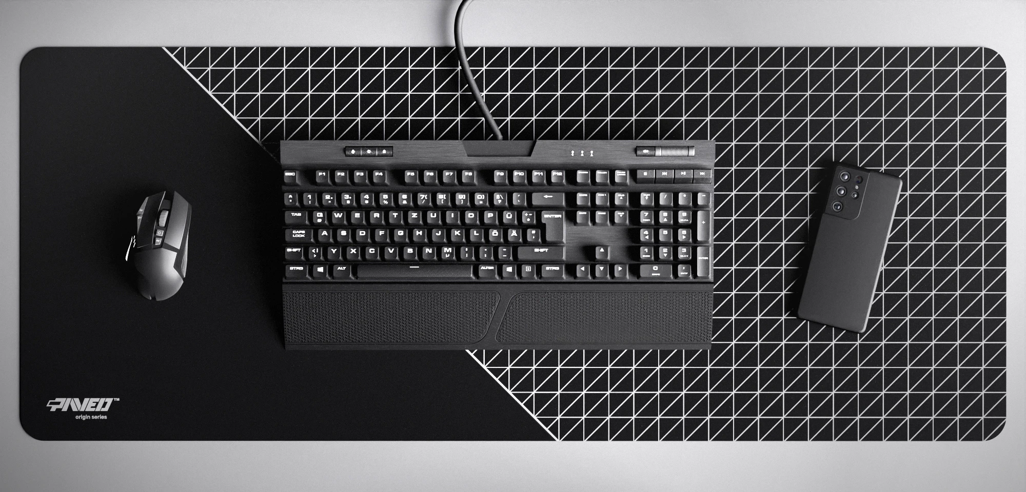 Top view of Night Net Runner XXL deskmat 1000mm x 400mm left-handed variant featuring dense geometric net pattern in white and black, water-resistant antimicrobial polyester surface, shown with full-size mechanical keyboard, gaming mouse, and smartphone for scale, ultra-lightweight odour-free AreoFlex microruber base, stitch-free professional finish.
