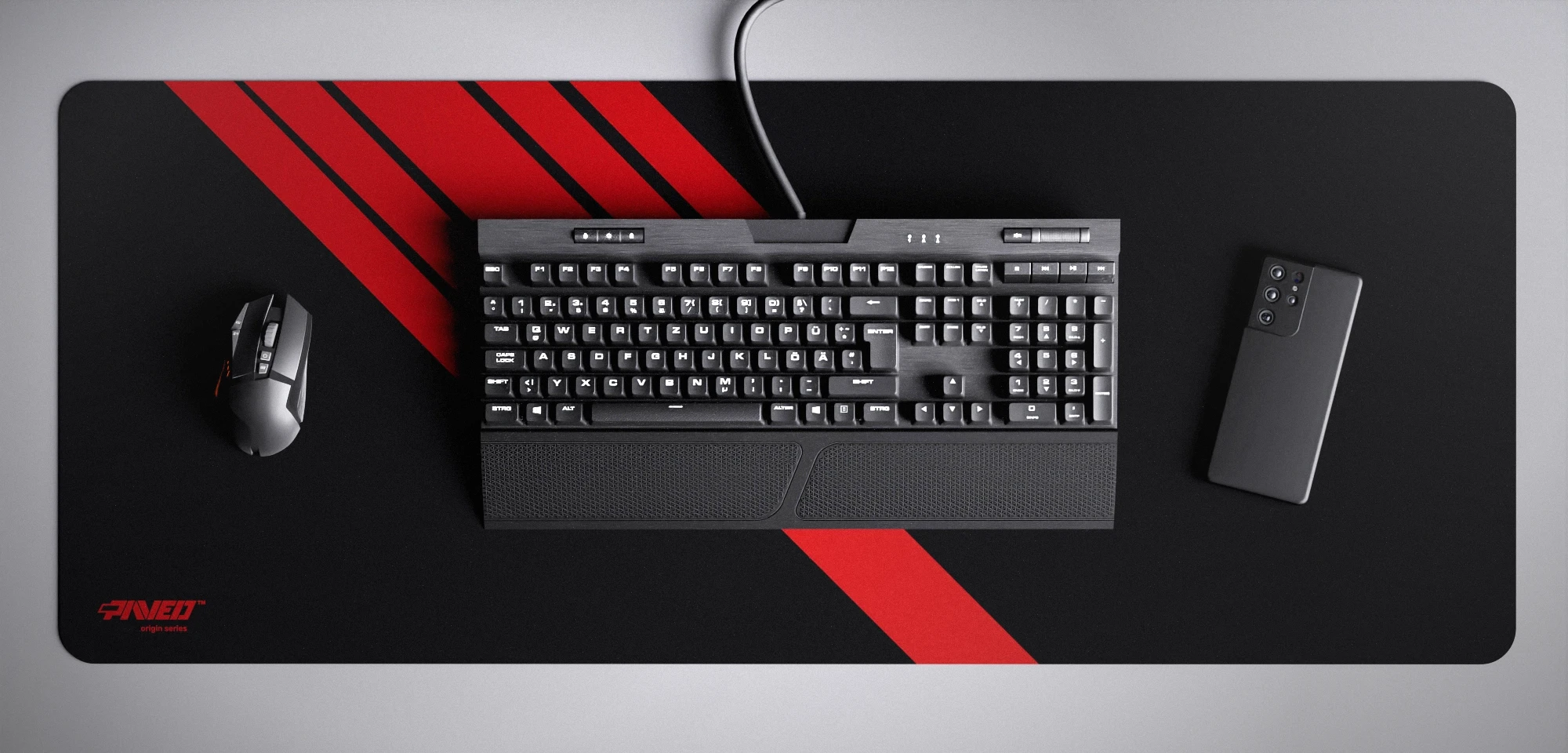 Top view of Night Imperial Blade Runner XXL deskmat 1000mm x 400mm left-handed variant featuring diagonal stripe design in red and black, water-resistant antimicrobial polyester surface, shown with full-size mechanical keyboard, gaming mouse, and smartphone for scale, ultra-lightweight odour-free AreoFlex microruber base, stitch-free professional finish.