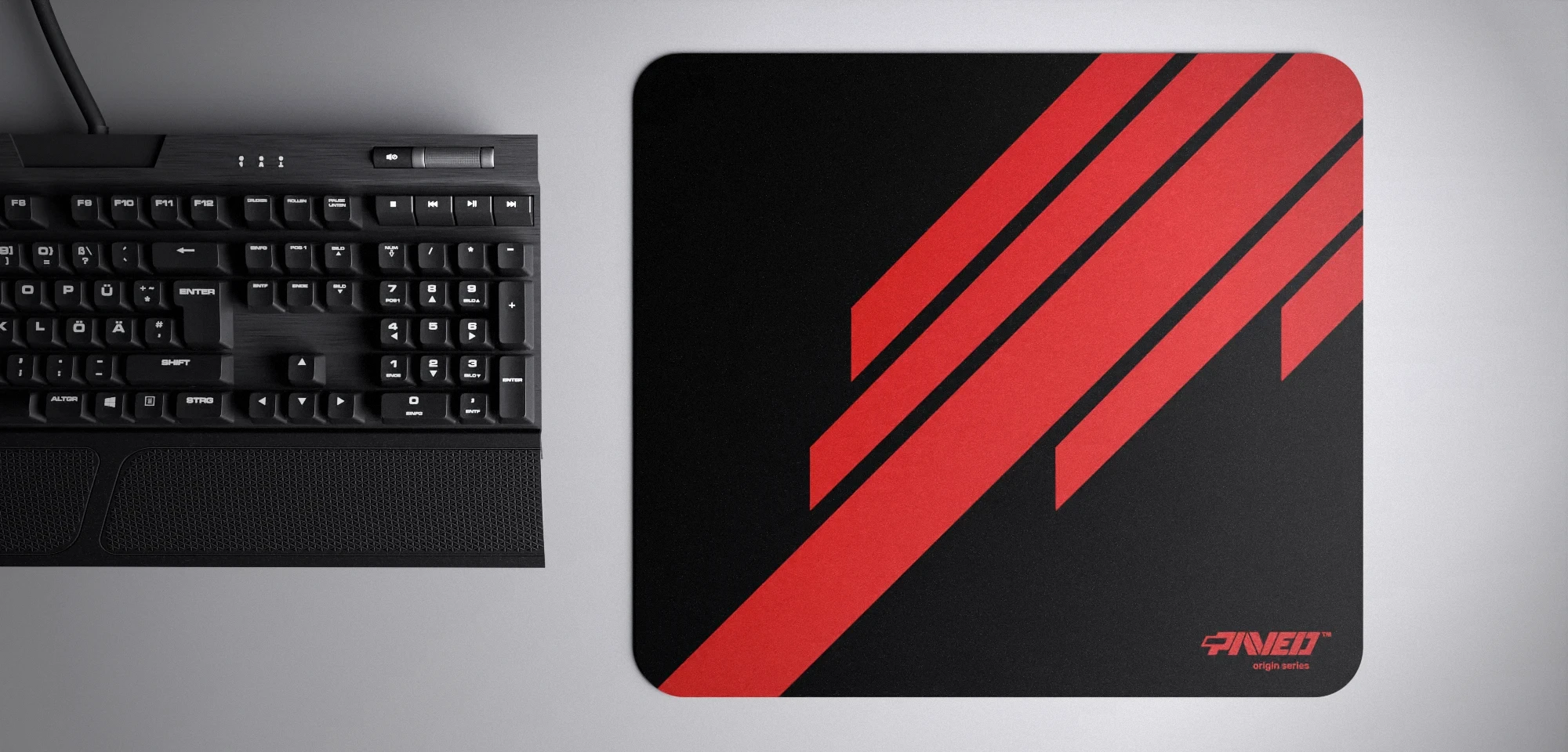 Top view of Night Imperial Blade Runner M size mousepad 360mm x 320mm right-handed variant with diagonal stripe design in red and black, hydrophobic easy-to-clean surface with antimicrobial properties, shown with full-size mechanical keyboard for scale, 600% lighter with no rubbery odour base, durable stitch-free finish.