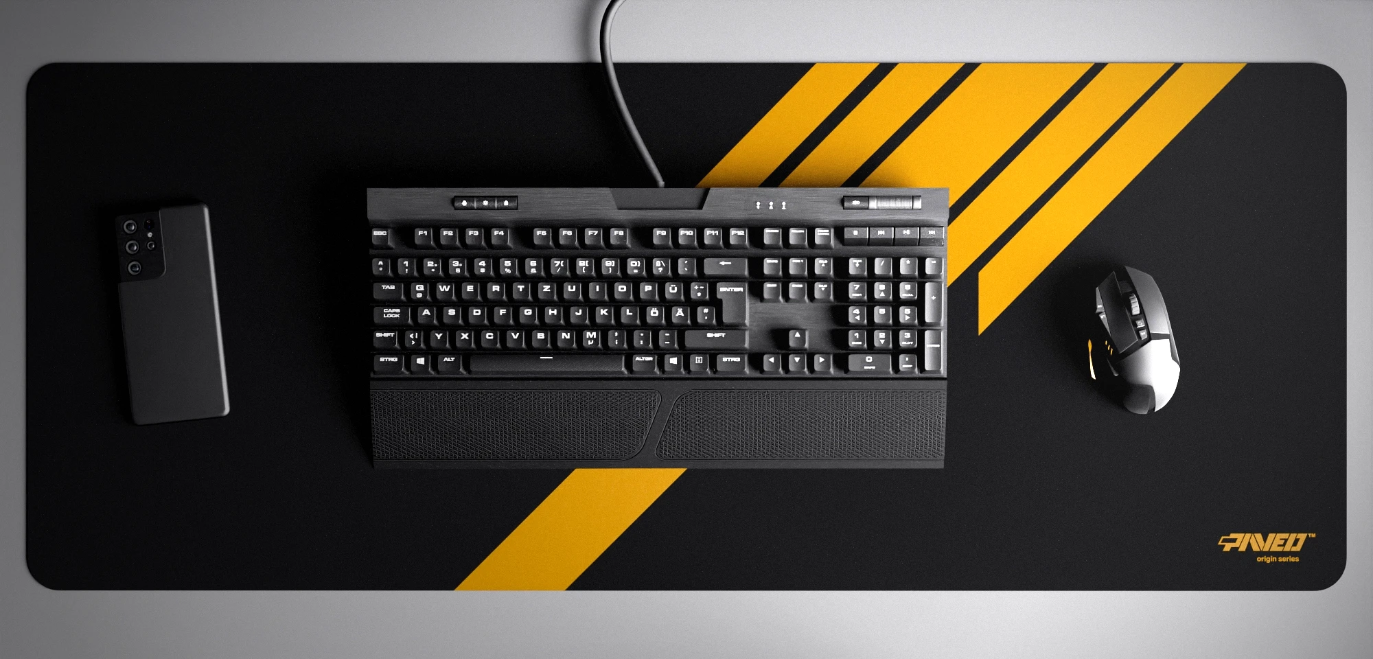 Top view of Night Desert Blade Runner XXL deskmat 1000mm x 400mm right-handed variant with minimalistic diagonal stripe design in deep yellow and black, hydrophobic easy-to-clean antimicrobial surface, shown with full-size mechanical keyboard, gaming mouse, and smartphone for scale, 600% lighter non-slip base with no rubbery smell, durable stitch-free edges.