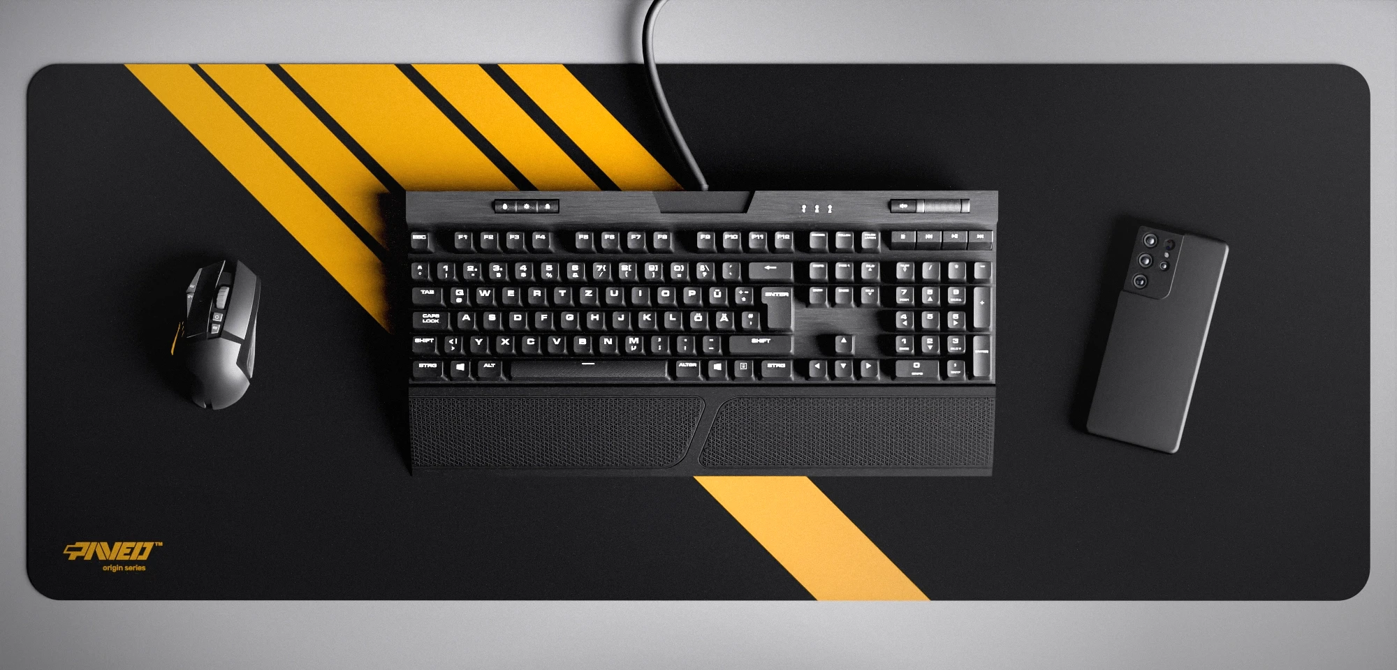 Top view of Night Desert Blade Runner XXL deskmat 1000mm x 400mm left-handed variant featuring diagonal stripe design in deep yellow and black, water-resistant antimicrobial polyester surface, shown with full-size mechanical keyboard, gaming mouse, and smartphone for scale, ultra-lightweight odour-free AreoFlex microruber base, stitch-free professional finish.